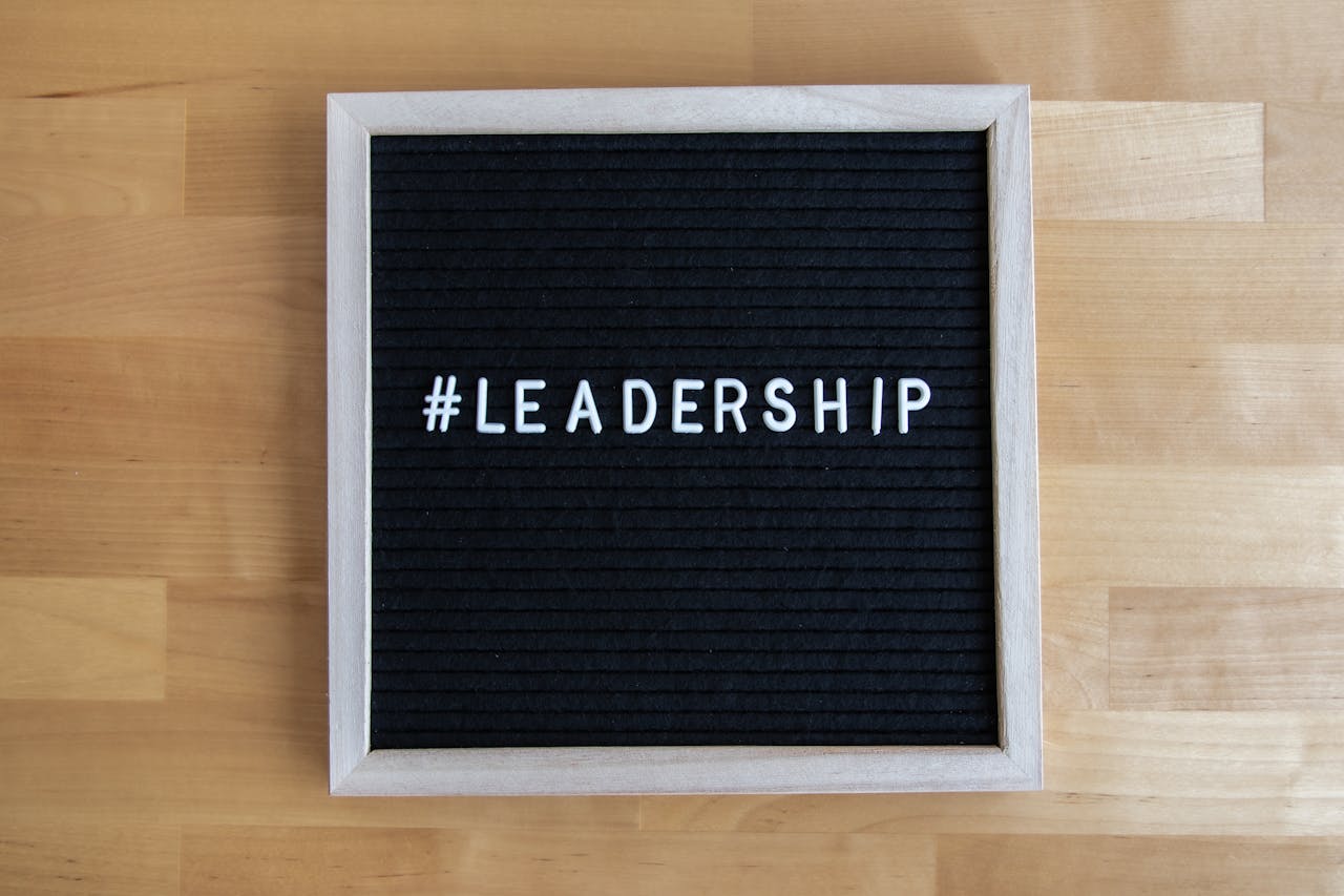 A black letter board with white hashtag leadership text on wooden surface, inspiring leadership theme.